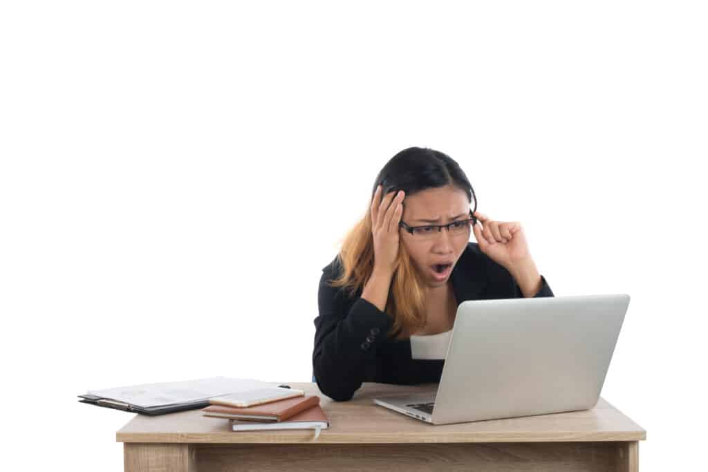 Stressed young business woman at the desk with a laptop isolated on white background.